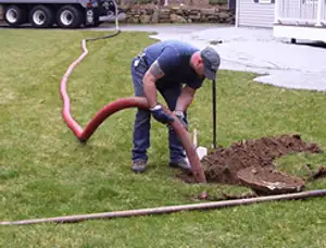 Septic pumping technician servicing a residential septic tank with a vacuum hose in Mountain View, CA