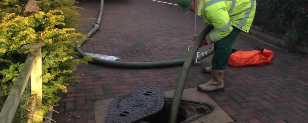 Septic tank cleaning technician servicing a septic tank with a vacuum hose in Mountain View, CA