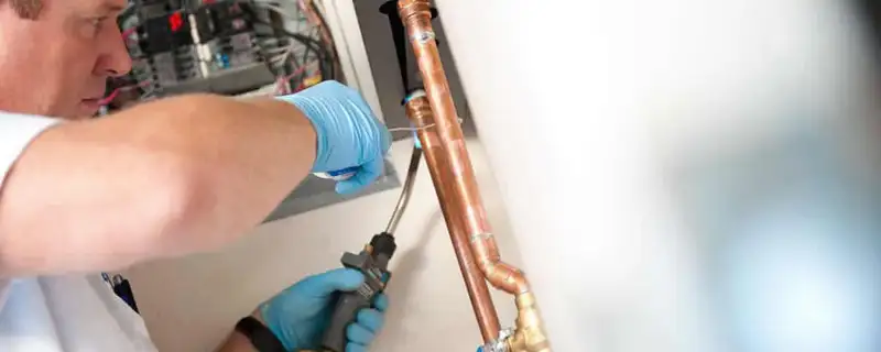 Water heater repair technician testing copper pipe connections and controls in Mountain View, CA